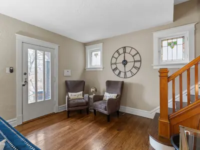 Entry foyer with stained glass windows, wall clock, and wood staircase