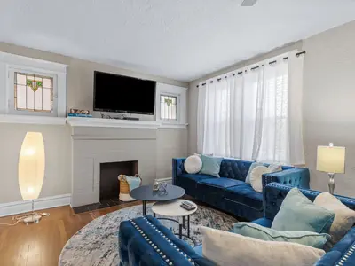 Living room with original brick fireplace, stained glass built-in cabinets, and blue tufted sofas