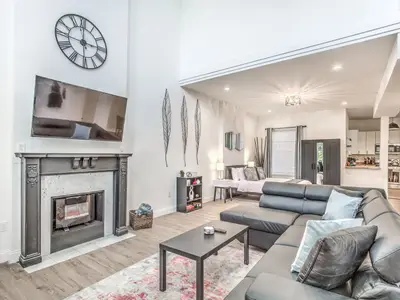 Ground-floor studio living area with fireplace mantel and leather sectional at 4632 McPherson (Hidden Gem)