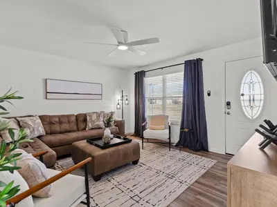 Living room with brown leather sectional sofa, ceiling fan, and front entry door with decorative oval glass window