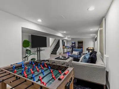 Basement game room with foosball table, arcade cabinets, and pinball machine